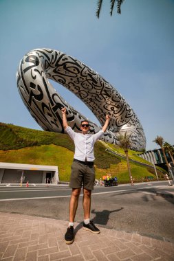 The Future Müzesi yakınlarındaki erkek turist - Dubai şehir merkezinde ExPO 2020 için inşa edilen Yeni Cazibe, Dış yüzeyinde Arap şiiri olan İnanılmaz Modern Mimari Tasarımı