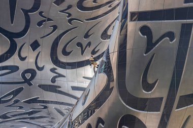 DUBAI / United Arab Emirates-8 / 11 / 2021 - Öğleden sonra Şeyh Zayed yolu yakınlarındaki gelecekteki müzeyi temizleyen erkekler. Dış yüzeyinde Arapça şiirler olan inanılmaz bir modern mimari tasarımı var.