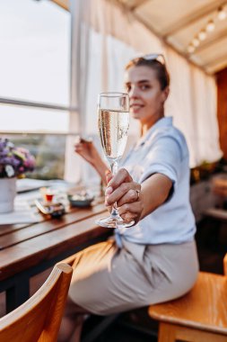 Yaz günbatımında taze istiridye yiyip soğuk Prosecco şarabı içen bir kadın. Deniz ürünleri lezzetleri.