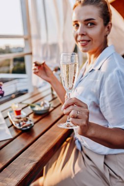 Yaz günbatımında taze istiridye yiyip soğuk Prosecco şarabı içen bir kadın. Deniz ürünleri lezzetleri.