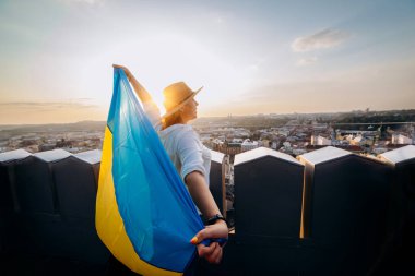 Ukrayna için dua edin. Bir adam Ukrayna bayrağının yanında duruyor ve gün batımında Lviv 'de barış için dua ediyor. Ukrayna halkının bir sembolü, bağımsızlık ve güç..