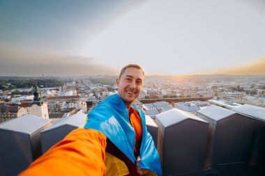 Ukrayna için dua edin. Bir adam Ukrayna bayrağının yanında duruyor ve gün batımında Lviv 'de barış için dua ediyor. Ukrayna halkının bir sembolü, bağımsızlık ve güç..