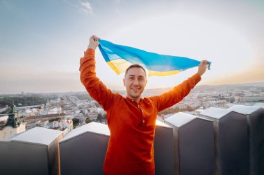 Ukrayna için dua edin. Bir adam Ukrayna bayrağının yanında duruyor ve gün batımında Lviv 'de barış için dua ediyor. Ukrayna halkının bir sembolü, bağımsızlık ve güç..