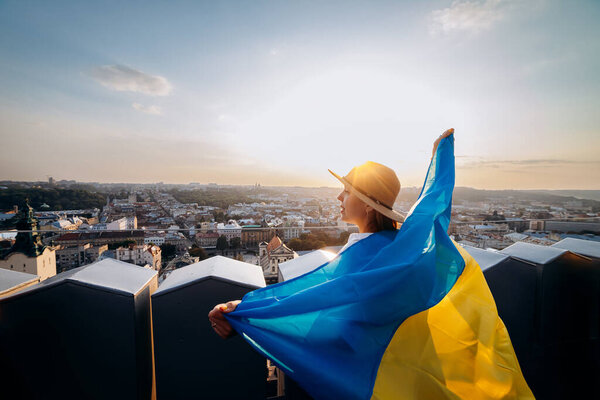 Pray for Ukraine.A man stands with the national Ukrainian flag and waving it praying for peace at sunset in Lviv.A symbol of the Ukrainian people, independence and strength.