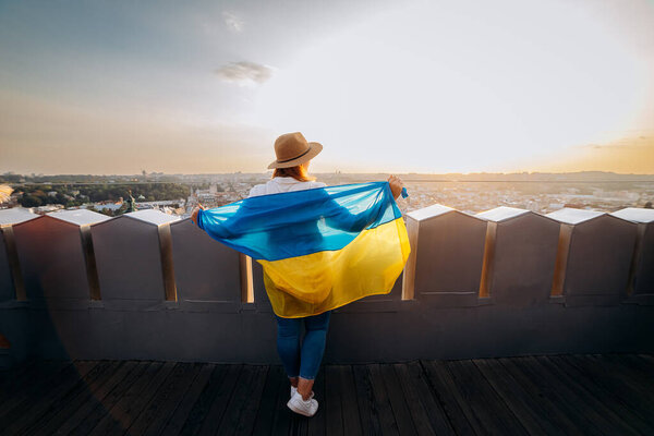 Pray for Ukraine.A man stands with the national Ukrainian flag and waving it praying for peace at sunset in Lviv.A symbol of the Ukrainian people, independence and strength.