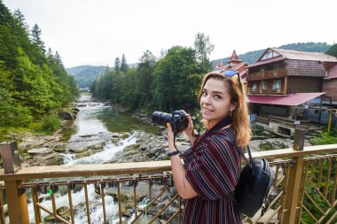 Kadın turist, Yaremche, Karpatlar, Ukrayna 'da Prut ve Şelale nehirlerinin fotoğraflarını çekiyor.