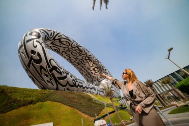 DUBAI / United Arab Emirates-8 / 11 / 2021 - Dubai şehir merkezinde ExPO 2020 için inşa edilen Geleceğin Müzesi yakınlarındaki Kadın Turist, Dış yüzeyinde Arap şiiri olan İnanılmaz Modern Mimari Tasarımı