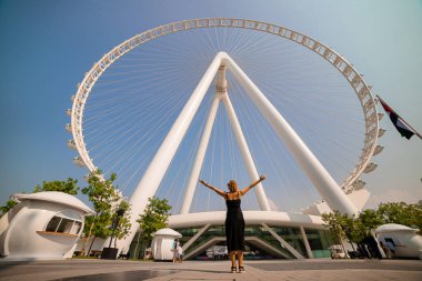 Kadın, Bluewater Adası 'ndaki dünyanın en büyük dönme dolaplarından biri olan Ain (Eye) DUBAI' yi görünce sevinçle ellerini kaldırdı. Birleşik Arap Emirlikleri 'nin en iyi turistleri arasında