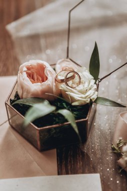 Alyanslar, düğün aksesuarı olarak çiçeklerle dolu güzel bir kutunun üzerinde duruyor. 