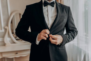 İş adamı ceket giyiyor, erkek eli kapalı, damat düğün töreninden önce hazırlanıyor.