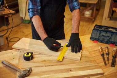 Marangoz bir ahşap ile çalışır, bir kalemle tahta işaretler ve ölçümler yapar bir marangoz atölyesinde bir parça mobilya yapmak için bir parça odun kesmek için, yakın görüş