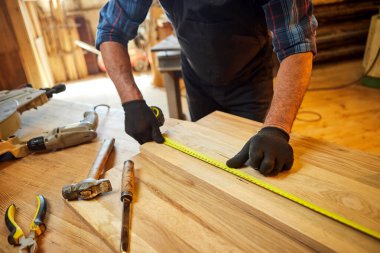 Marangoz bir ahşap ile çalışır, bir kalemle tahta işaretler ve ölçümler yapar bir marangoz atölyesinde bir parça mobilya yapmak için bir parça odun kesmek için, yakın görüş