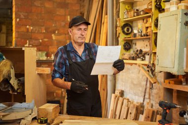 Üst düzey bir marangozun portresi marangozluk atölyesinde mobilya yapmayı planlıyor.