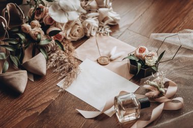 Ayakkabı, buket, yüzük ve parfüm gibi düğün aksesuarları bir masanın üzerinde bulunur.