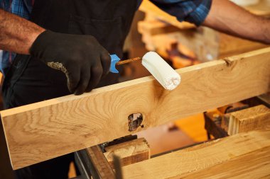 Üniformalı kıdemli marangoz marangozda el baskısıyla tahta parmaklıkları yapıştırıyor.