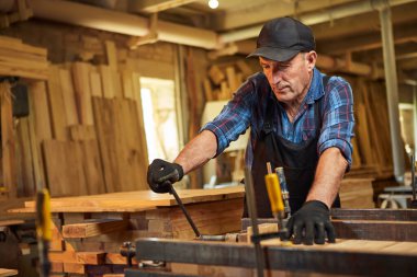 Üniformalı bir marangozun portresi marangozluk fabrikasında ahşap parmaklıkları el baskısıyla yapıştırıyor.