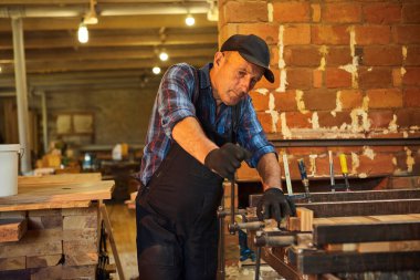 Üniformalı bir marangozun portresi marangozluk fabrikasında ahşap parmaklıkları el baskısıyla yapıştırıyor.