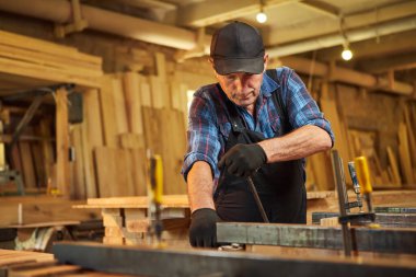 Üniformalı bir marangozun portresi marangozluk fabrikasında ahşap parmaklıkları el baskısıyla yapıştırıyor.