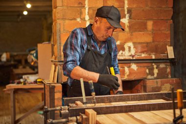 Üniformalı bir marangozun portresi marangozluk fabrikasında ahşap parmaklıkları el baskısıyla yapıştırıyor.