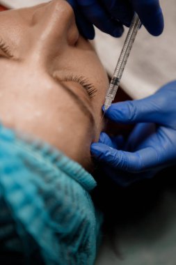 Bir kozmetikçi hastasına bir şırınga enjekte eder, Botoks.