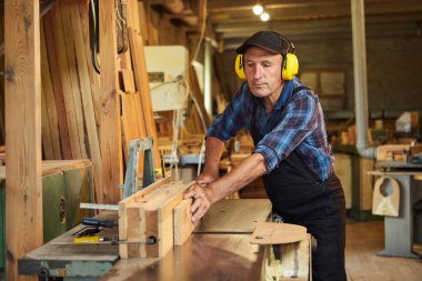 Üniformalı kıdemli marangoz marangozluk fabrikasında marangoz olarak çalışıyor.