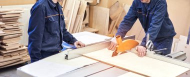 Elektrikli testere ile ahşap kesme masası. Marangozluk atölyesinde usta bir dolap ustası var. Profesyonel marangoz kereste fabrikasında tahta kesiyor. Testere makinesi