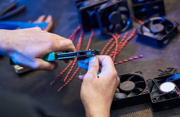 A master technologist makes fans for a computer cooling system. Computer Fan Parts lie on the table