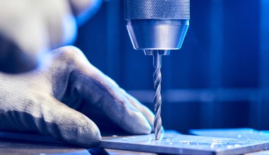 Çalışan, alüminyum düz çelik plaka ve bank matkabı sondajı yapıyor. Metal matkap kısmı endüstriyel makinede çelik bölmede delikler açıyor. Metal iş endüstrisi. Kapat.