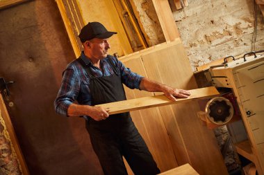 Üniformalı kıdemli marangoz marangozluk fabrikasında ahşap işçiliği yapıyor. 