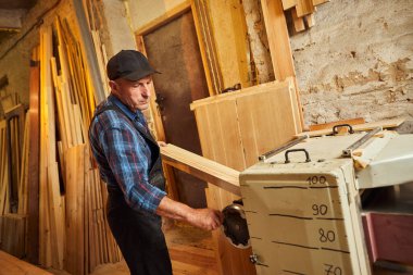 Üniformalı kıdemli marangoz marangozluk fabrikasında ahşap işçiliği yapıyor. 