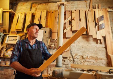 Üniformalı kıdemli marangoz marangozluk fabrikasında ahşap işçiliği yapıyor. 