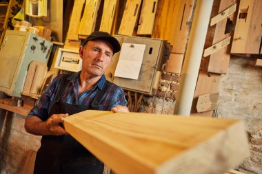 Üniformalı kıdemli marangoz marangozluk fabrikasında ahşap işçiliği yapıyor. 