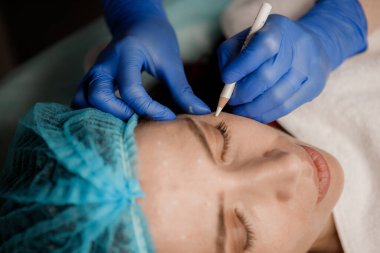 Kozmetik uzmanı hastayı botoks ameliyatına hazırlıyor.