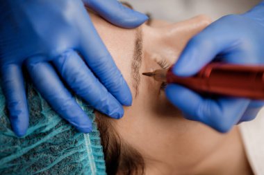 Genç kadın dövme salonu, closeup kalıcı dudak makyaj prosedürü geçiren