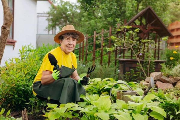 Bahçesinde çalışan bir bahçıvan kadının portresi. Bahçe işleri, çiçek ve bitkilerle ilgilenmek ve büyümek..