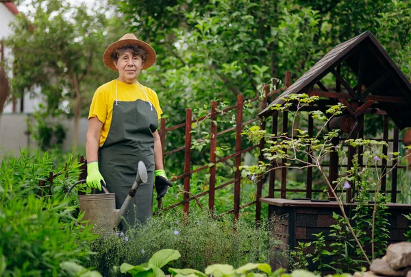 Bahçesinde çalışan bir bahçıvan kadının portresi. Bahçe işleri, çiçek ve bitkilerle ilgilenmek ve büyümek..