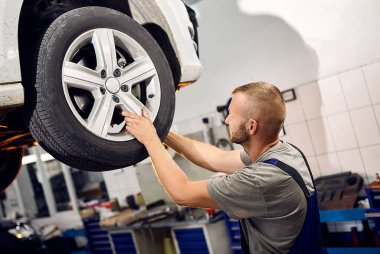 Otomobil tamircisi, benzin istasyonunda çalışan otomobili kontrol ediyor. Erkek işçi arabayla ilgili sorunu düzeltiyor. Araç bakımı kavramı