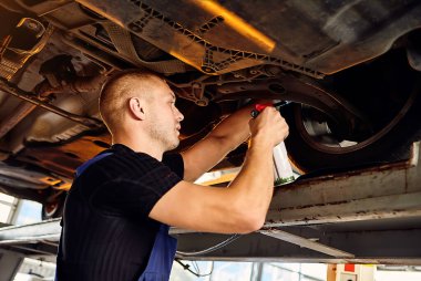 Otomobil tamircisi, benzin istasyonunda çalışan otomobili kontrol ediyor. Erkek işçi arabayla ilgili sorunu düzeltiyor. Araç bakımı kavramı