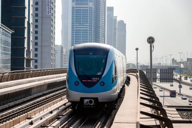 Dubai, Birleşik Arap Emirlikleri - 08 Kasım 2021: Dubai metro treni gökdelenlerin arka planında. Meşhur metro kırmızı hattı.