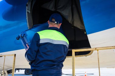 Bagajları uçağa yüklüyorum. Havaalanı çalışanı bagajları uçağa yüklüyor.