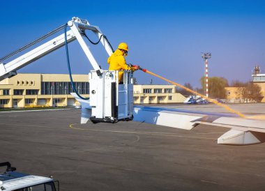 Uzman, havaalanında uçağı antifriz ile tedavi ediyor. Havaalanındaki bir uçak kanadında buz çözücü sıvı püskürtme işlemi.