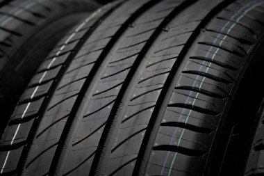 Yeni araba lastikleri. Karanlık arka planda bir grup yol tekeri. Asimetrik lastik dizaynlı yaz lastikleri. Araba konsepti. Yakın plan.