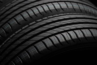 Yeni araba lastikleri. Karanlık arka planda bir grup yol tekeri. Asimetrik lastik dizaynlı yaz lastikleri. Araba konsepti. Yakın plan.