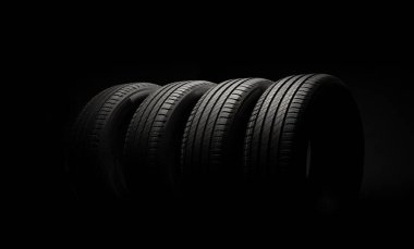 Yeni araba lastikleri. Karanlık arka planda bir grup yol tekeri. Asimetrik lastik dizaynlı yaz lastikleri. Araba sürme kavramı.
