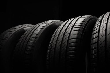 Yeni araba lastikleri. Karanlık arka planda bir grup yol tekeri. Asimetrik lastik dizaynlı yaz lastikleri. Araba sürme kavramı.