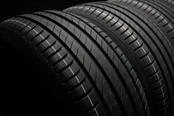 Yeni araba lastikleri. Karanlık arka planda bir grup yol tekeri. Asimetrik lastik dizaynlı yaz lastikleri. Araba sürme kavramı.