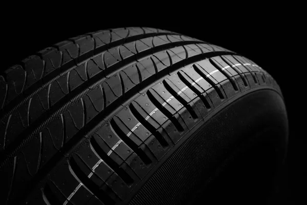 新车轮胎 黑暗背景下的方向盘 夏季轮胎与不对称的胎面设计 驾驶汽车的概念 — 图库照片