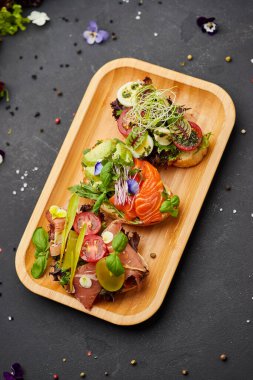 Somon, parma ve pesto soslu çeşitli bruschetta seti. İtalyan antipasti atıştırmalıkları. Koyu arkaplanda küçük sandviçlerin çeşitli karışımları. Restoran menüsü için fotoğraf