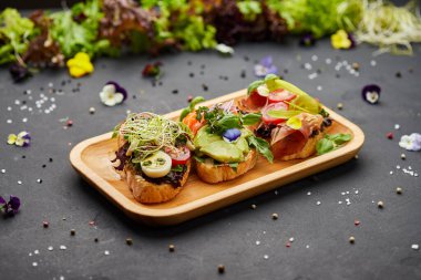Somon, parma ve pesto soslu çeşitli bruschetta seti. İtalyan antipasti atıştırmalıkları. Koyu arkaplanda küçük sandviçlerin çeşitli karışımları. Restoran menüsü için fotoğraf