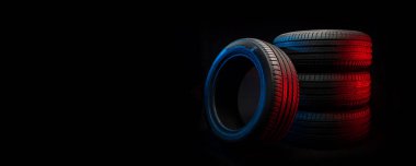 Yeni araba lastikleri. Karanlık arka planda bir grup yol tekeri. Asimetrik lastik dizaynlı yaz lastikleri. Araba sürme kavramı.